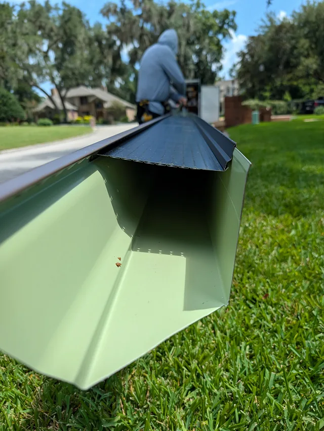 Open end of a gutter section with a perforated guard during on-site assembly.