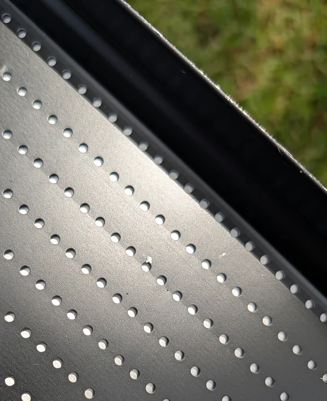 Close-up of the perforated aluminum surface of a gutter guard.