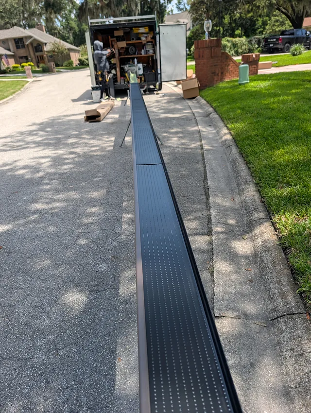 Gutter sections being prepared on stands beside the installation crew vehicle.