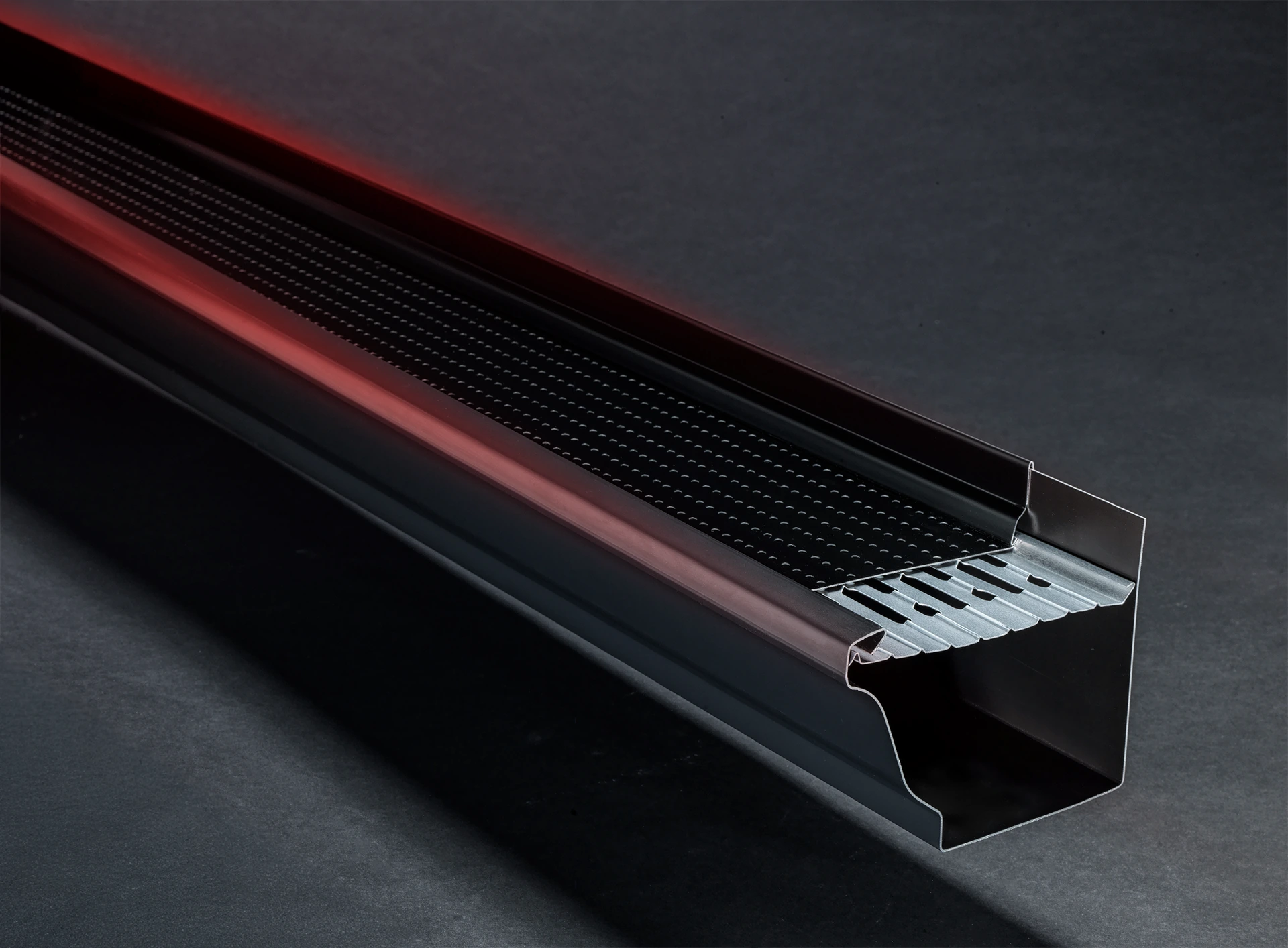 Dual-layer aluminum gutter guard on a gutter section with the lower slotted membrane exposed at the end